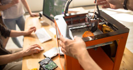 A 3D printer being used by a group of people. This is just one example of the acceleration of the 4th industrial revolution. Read more on Sourcengine about where the industry is going.