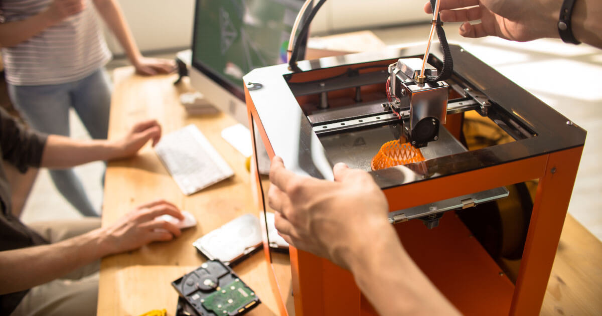 A 3D printer being used by a group of people. This is just one example of the acceleration of the 4th industrial revolution. Read more on Sourcengine about where the industry is going.