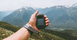 A hiker holding a GPS unit while navigating a mountain region; Unictron's Castle Patch Antenna is uniquely suited for GPS and other positioning devices; find out more at Sourcengine. 