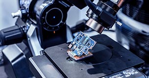 Microchip being produced under a power microscopic lens; passive and reactive component lead times have increased during the global chip shortage. Are you prepared? Try using sourcengine.com for all your sourcing needs.