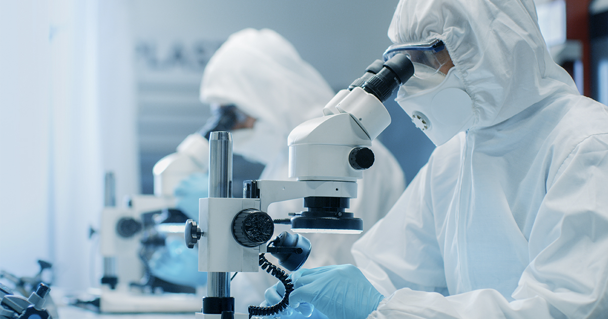 Two engineers in clean room suits look into microscopes inside a chip factory | Sourcengine