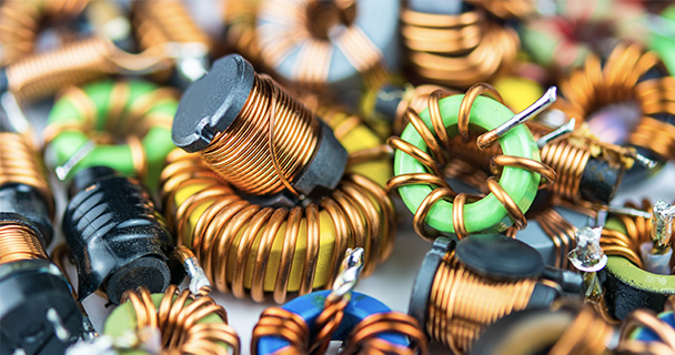 A closeup on a pile of inductors with copper winding and one with magnetic core. | Sourcengine