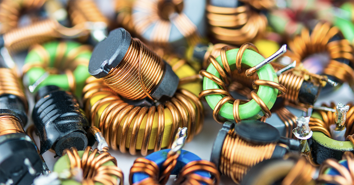 A closeup on a pile of inductors with copper winding and one with magnetic core. | Sourcengine