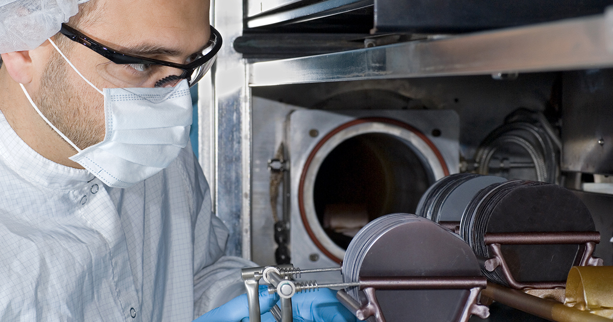 A technician works with a stack of silicon wafers inside a fab clean room | Sourcengine 