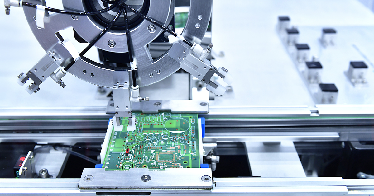 An autonomous robotic arm in the process of assembling a printed circuit board.