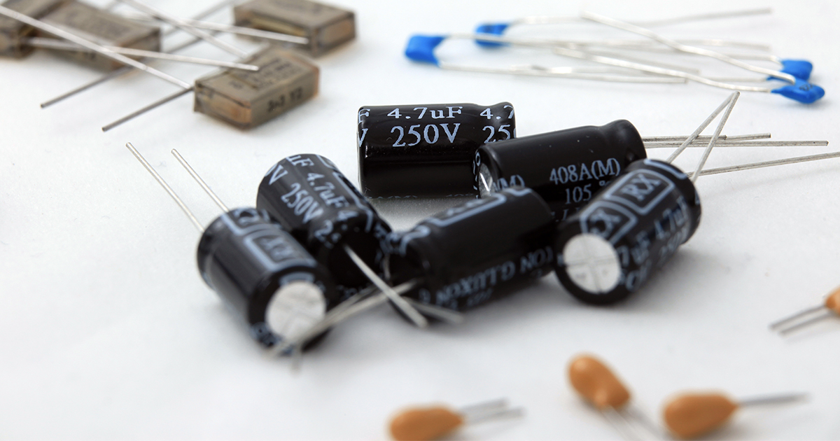 Four piles of electronic capacitors of various sizes and types. | Sourcengine 