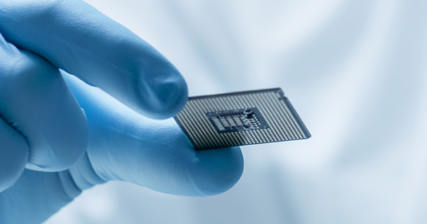 A close-up of an engineer in personal protective gear inspecting a CPU.