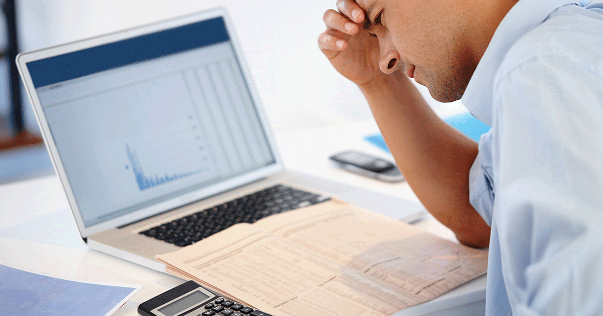 A professional buyer looks frustrated while staring at a bill of materials (BOM) at their work desk.