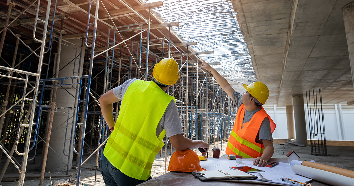 Two engineers examining blueprints at a construction site