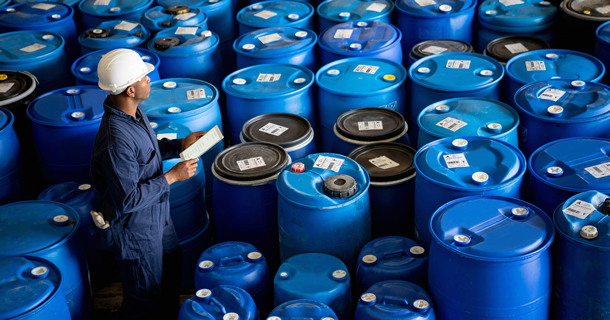 An image of an engineer surrounded by chemical barrels
