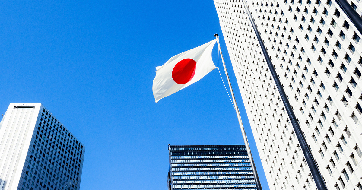 An image of the Japanese flag flying among buildings on a sunny day